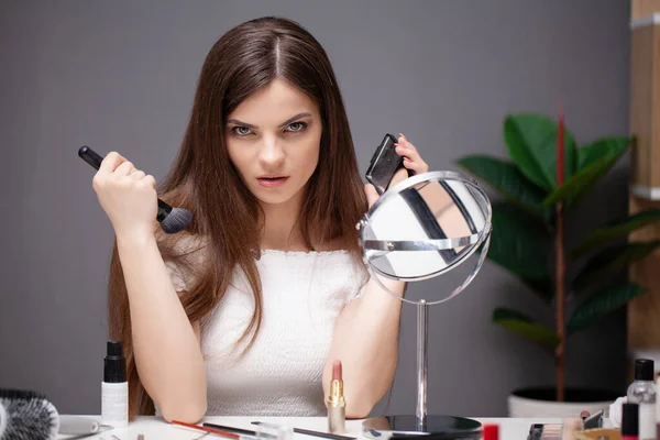 Mujer joven que aplica maquillaje en la cara en casa —  Fotos de Stock