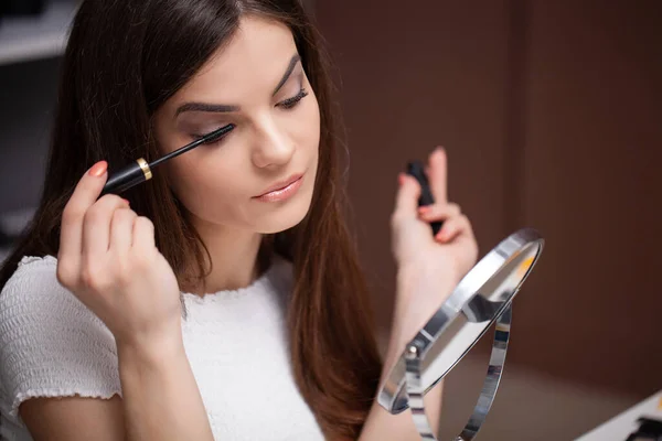 Mujer joven que aplica maquillaje en la cara en casa —  Fotos de Stock