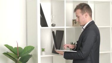 İş yerinde dizüstü bilgisayarda yazan başarılı genç işadamı