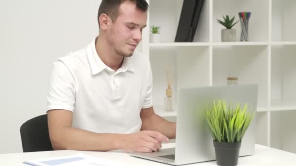 Успішний молодий бізнесмен друкує на ноутбуці на робочому місці — стокове відео