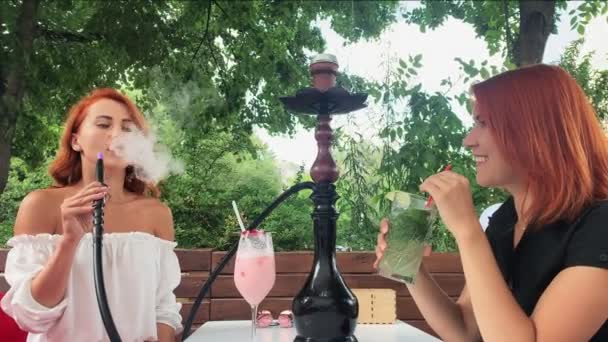 Chicas con pelo rojo humo hookah en la terraza — Vídeo de stock