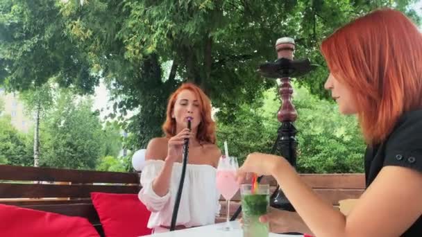 Girls with red hair smoke hookah on the terrace — Stock Video