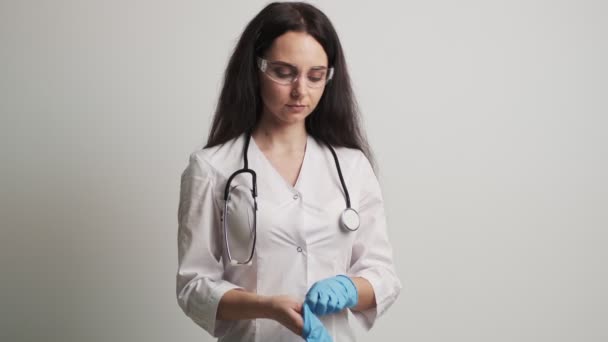 Vrouwelijke arts in een witte jas draagt beschermende handschoenen — Stockvideo