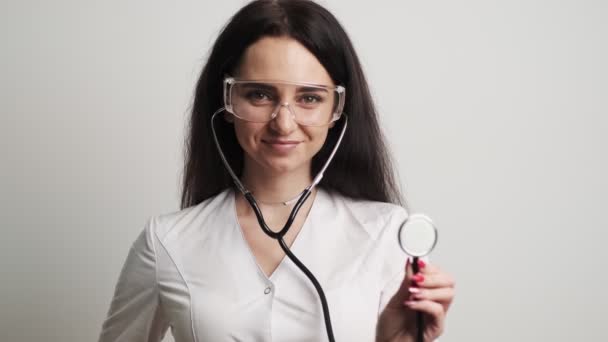 Kvinna läkare med glasögon och med ett fonoskop poserar för kameran — Stockvideo