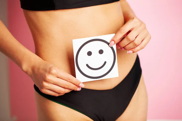 Mujer sosteniendo papel con una sonrisa en el estómago. Salud higiene educación sexual concepto. — Foto de Stock