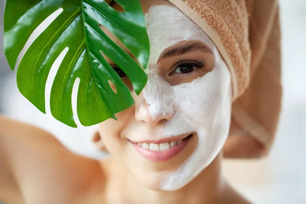 Retrato de cerca de una hermosa chica con una toalla en la cabeza aplicando mascarilla facial — Foto de Stock