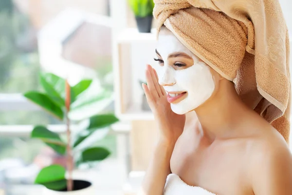 Close-up portrait of beautiful girl with a towel on her head applying facial mask — Stock Photo, Image