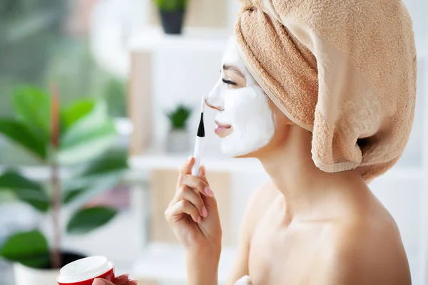 Atractiva mujer divertida con una máscara de barro en la cara. — Foto de Stock
