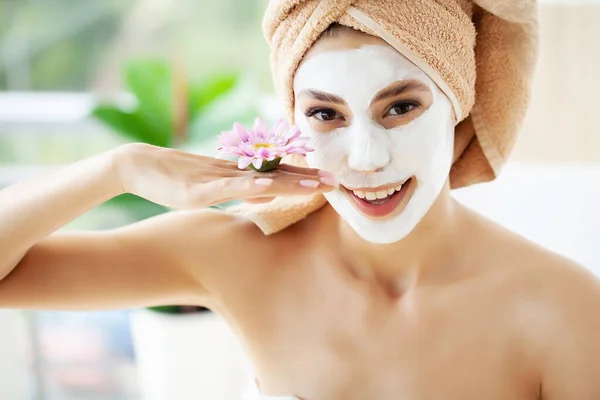 Atractiva mujer divertida con una máscara de barro en la cara. — Foto de Stock