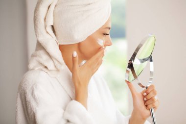 Cilt bakımı, güzel bir model yüzüne kozmetik krem sürüyor.