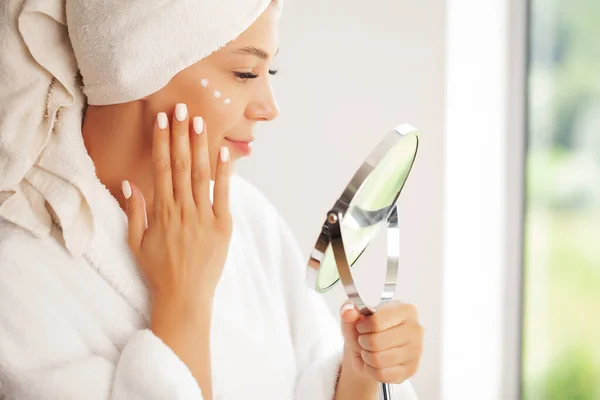 Hautpflege: Schönes Model trägt kosmetische Creme auf ihr Gesicht auf — Stockfoto