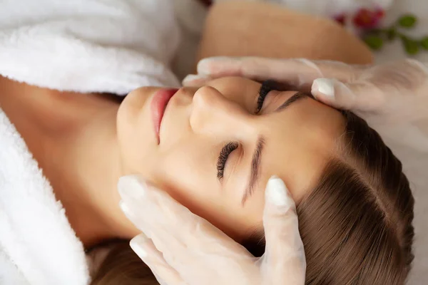 Giovane donna godendo di massaggio facciale nel salone spa — Foto Stock