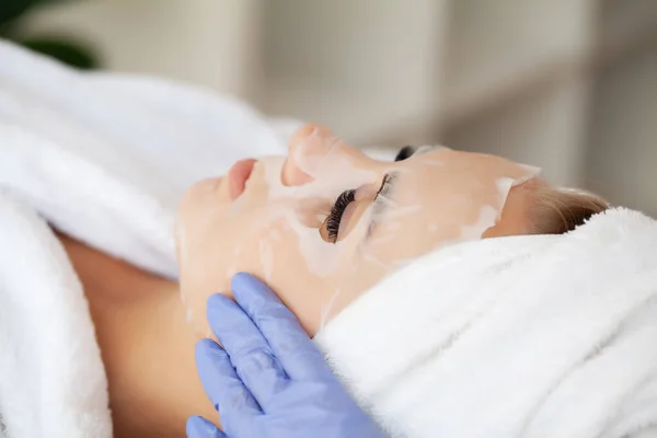 Cuidados com a pele, mulher bonita com máscara facial no salão de beleza — Fotografia de Stock