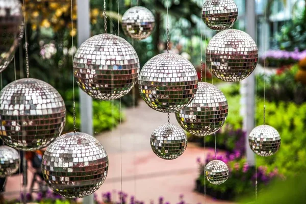 Disco balls, mirror balls hanging outside in the garden. Bright reflective mirror disco balls.