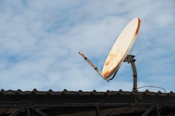 Kaputte und alte Satellitenschüssel auf dem Dach und blauer Himmel Hintergrund. — Stockfoto