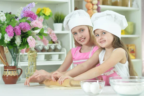 自宅の台所で生地を作るシェフ帽子でかわいい女の子 — ストック写真