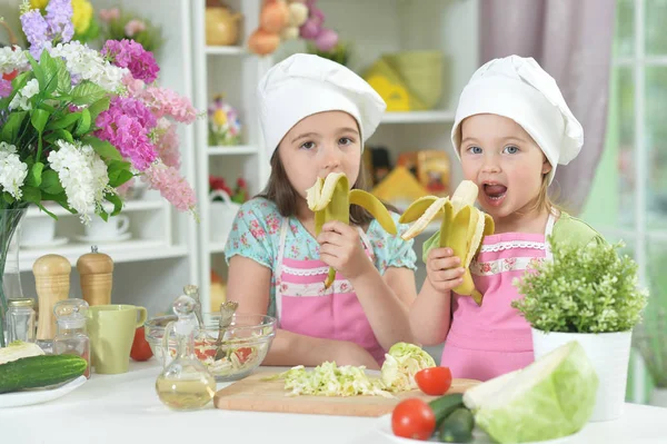 Dos Niñas Adorables Delantales Comiendo Plátanos Cocina —  Fotos de Stock