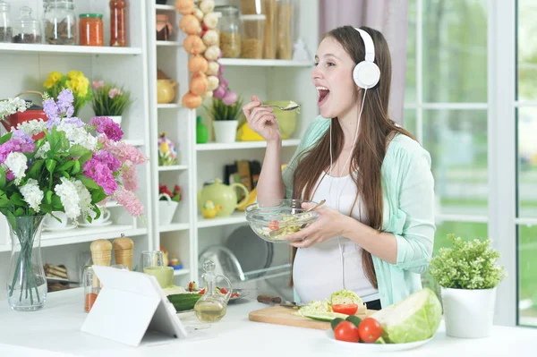 Piękna Kobieta Ciąży Słuchawkach Jedzenie Kuchnia — Zdjęcie stockowe