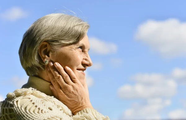 Счастливая пожилая женщина позирует против неба — стоковое фото