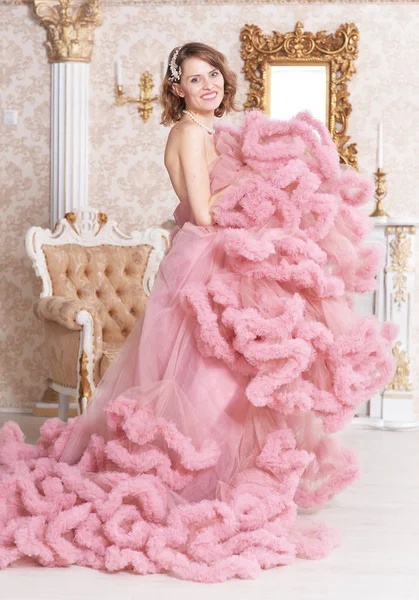 漂亮的年轻女子在粉红色的礼服摆在室内老式内饰 — 图库照片