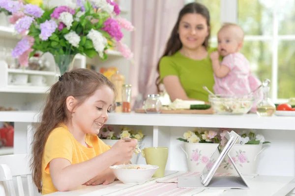 Söt Liten Flicka Äter Fräsch Sallad Köksbordet Med Surfplatta Det — Stockfoto