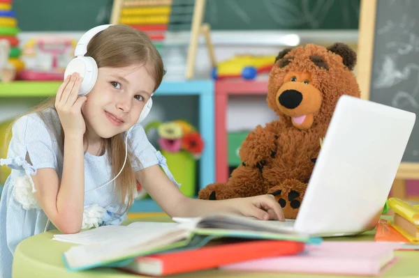 Schattig Schoolmeisje Hoofdtelefoons Aan Tafel Met Laptop Thuis Studeren — Stockfoto