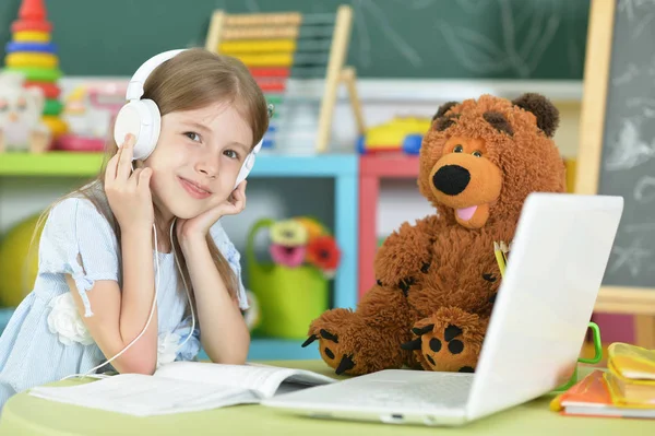 Schattig Schoolmeisje Hoofdtelefoons Aan Tafel Met Laptop Thuis Studeren — Stockfoto