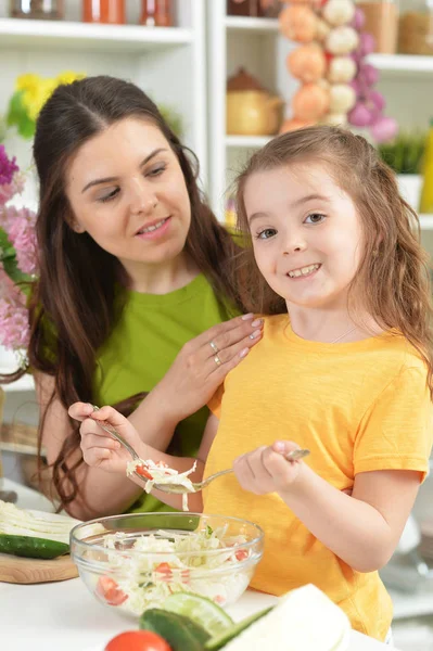 可愛いです女の子とともに彼女のお母さん料理とともにキッチンテーブル — ストック写真