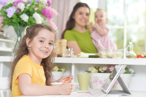 Söt Liten Flicka Äter Fräsch Sallad Köksbordet Med Surfplatta Det — Stockfoto