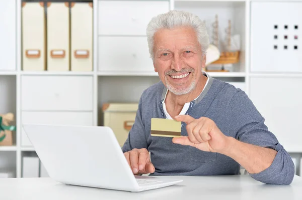 クレジット カードを保持している オンライン ショッピングのコンセプトのラップトップで年配の男性 — ストック写真