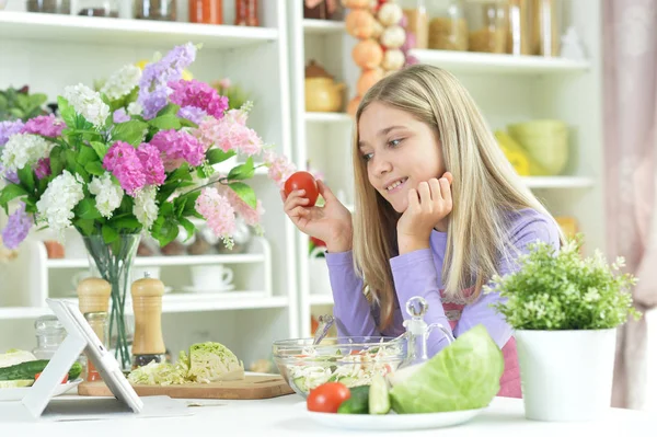 Linda Niña Sosteniendo Tomate Mirando Tableta Mientras Prepara Ensalada Fresca — Foto de Stock