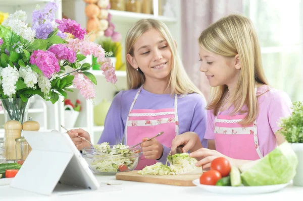 Two Girls Pink Aprons Preparing Fresh Salad Kitchen Table Tablet — Stock Photo, Image