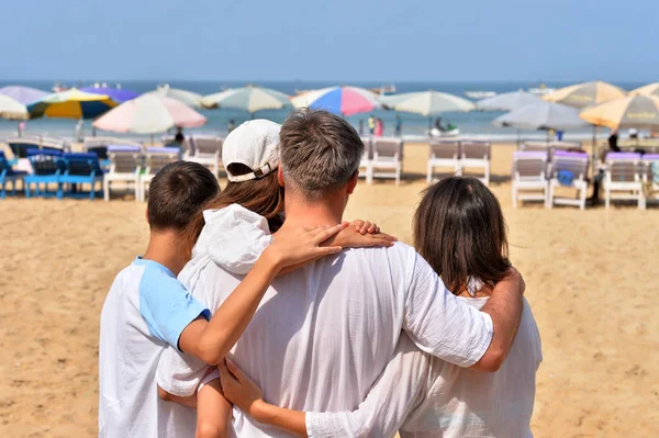 Семья сидит на песчаном пляже — стоковое фото