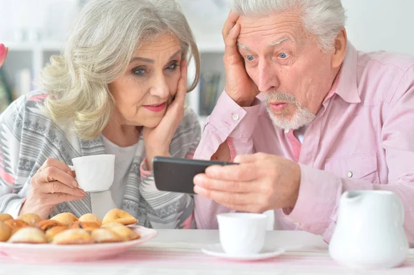 Glückliches Senioren Paar Schaut Beim Teetrinken Der Küche Aufs Smartphone — Stockfoto