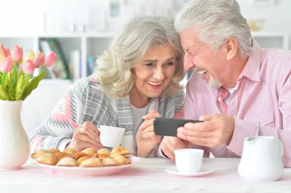 Glückliches Senioren Paar Schaut Beim Teetrinken Der Küche Aufs Smartphone — Stockfoto