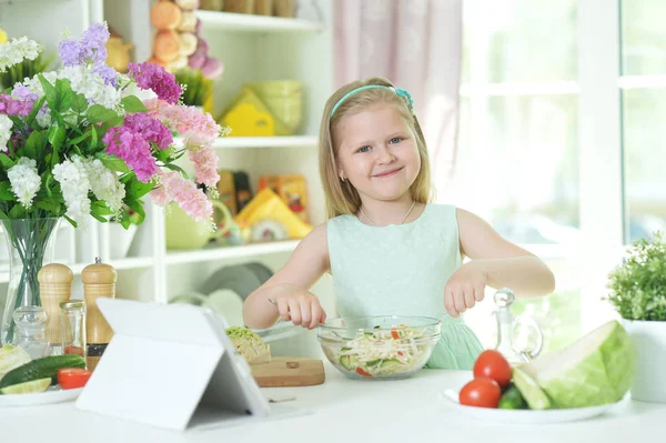 Симпатична Маленька Дівчинка Готує Салат Кухонному Столі Планшетом Вдома — стокове фото