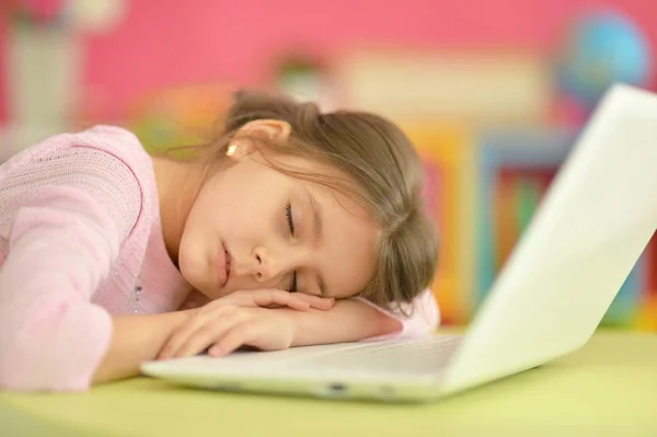 Милая маленькая девочка спит рядом с ноутбуком — стоковое фото