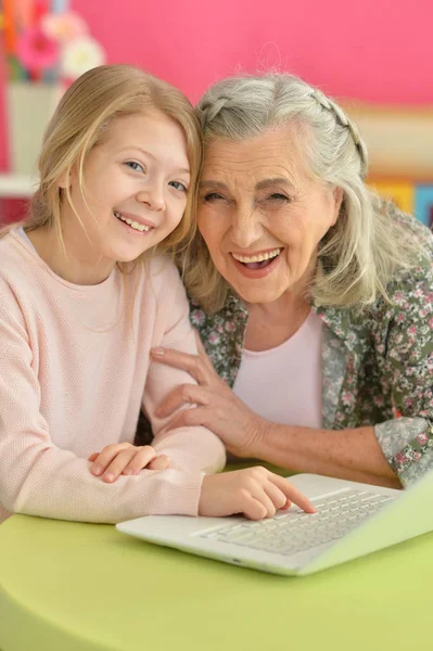 Chica con la abuela usando el ordenador portátil — Foto de Stock