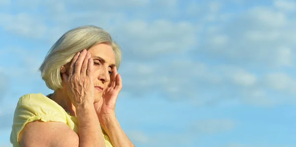 Traurige Ältere Frau Mit Kopfschmerzen Gegen Blauen Himmel — Stockfoto