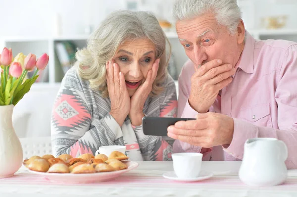 Glückliches Senioren Paar Schaut Beim Teetrinken Der Küche Aufs Smartphone — Stockfoto