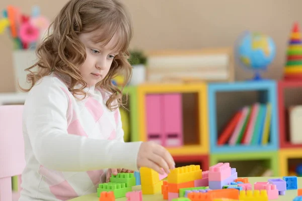 巻き毛の小さな女の子が彼女の部屋でカラフルなプラスチック製のブロックで遊んで — ストック写真