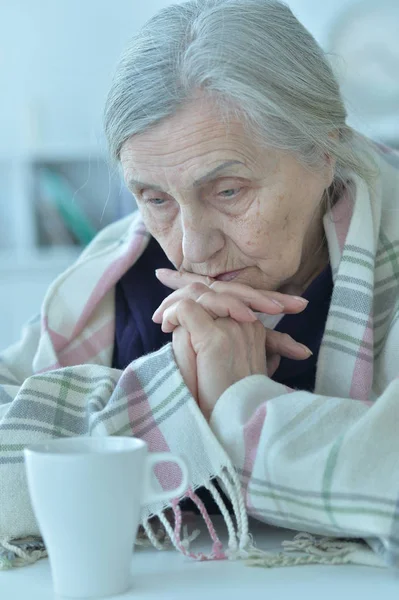 Portrait of a sad old woman wearing plaid