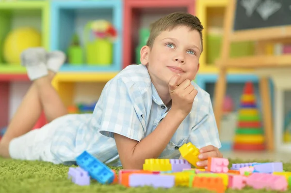 微笑的男孩在地板上玩五颜六色的塑料块 — 图库照片