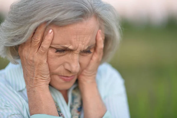 Portret Senior Kobieta Zatroskana Bólem Głowy Parku — Zdjęcie stockowe