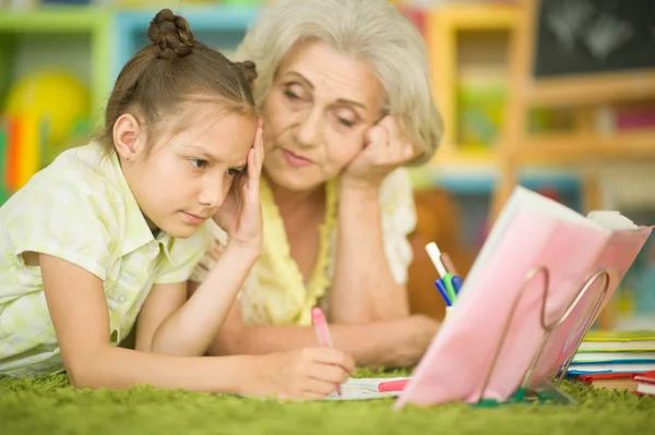 Mormor Med Söt Liten Flicka Göra Läxor Tillsammans Liggande Golvet — Stockfoto