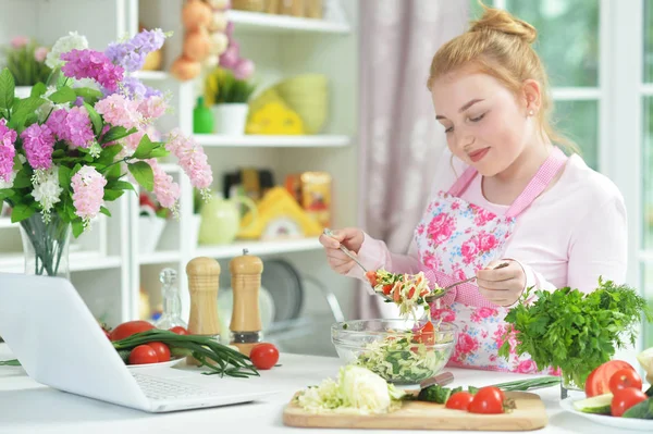 台所のテーブルに新鮮なサラダを準備するかわいい十代の少女 — ストック写真