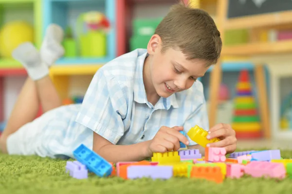微笑的男孩在地板上玩五颜六色的塑料块 — 图库照片