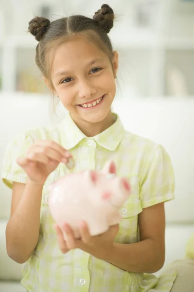 Schattig Klein Meisje Met Een Spaarvarken Bank Thuis — Stockfoto