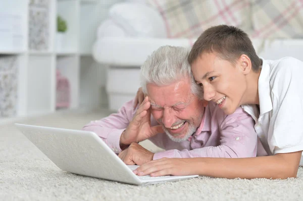 Avô Com Neto Usando Laptop Enquanto Deitado Chão Casa — Fotografia de Stock