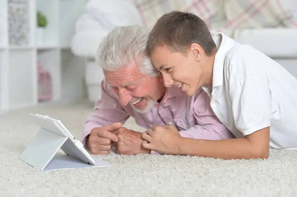 Dziadek Wnukiem Pomocą Tabletu Leżąc Podłodze Domu — Zdjęcie stockowe